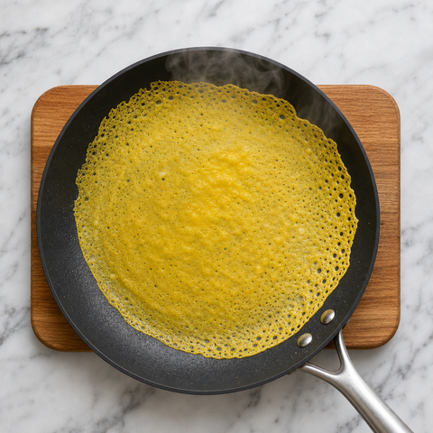 Pastella sottile alla curcuma distribuita in una padella calda per il banh xeo