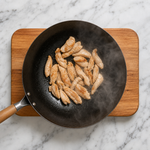 Sliced chicken browning in a hot wok