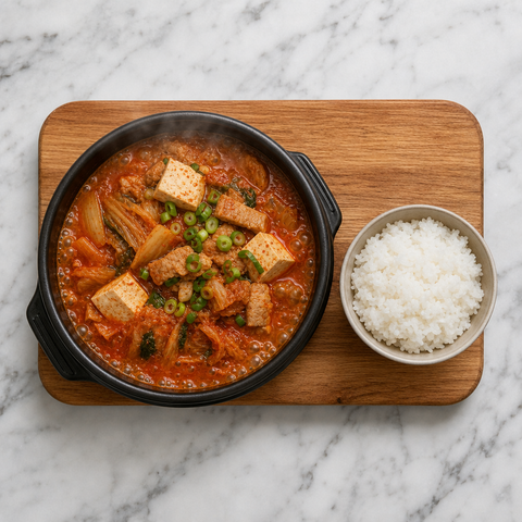 Cuenco de guiso coreano de kimchi con panceta de cerdo, tofu, kimchi, cebolleta y arroz.