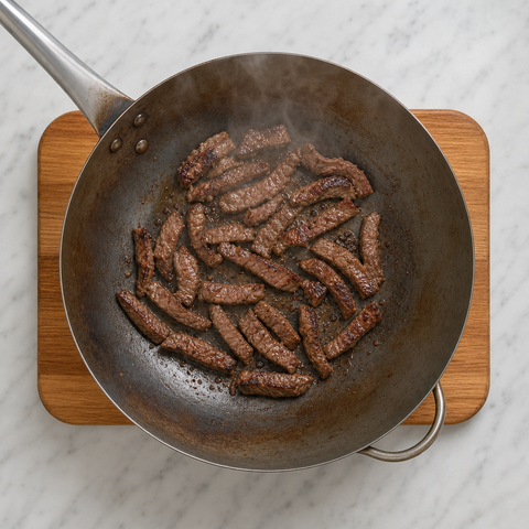 Lanières de bœuf saisies aux bords dorés dans un wok très chaud