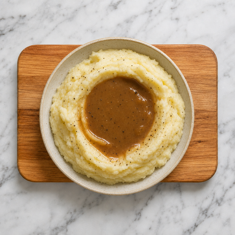 Mashed potatoes topped with glossy gravy in a serving bowl