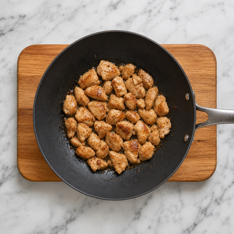 Browned chicken pieces cooking in a wok