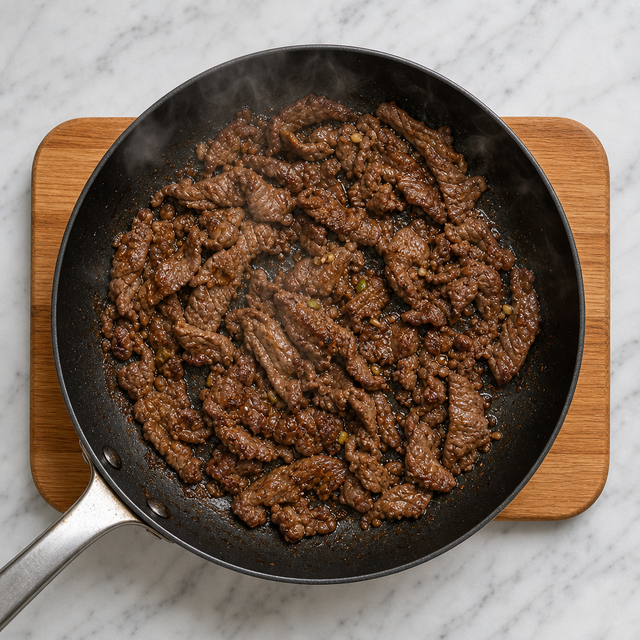 Thinly sliced beef browning in a skillet